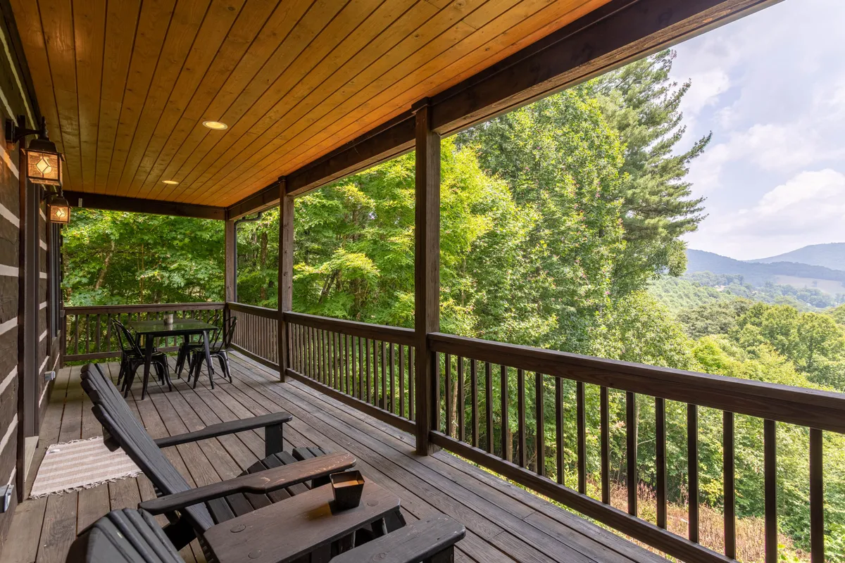 A wooden deck perched above scenic mountains, equipped with cozy outdoor seating and lanterns. The view stretches to rolling hills and forests, offering a peaceful spot for families to relax after a day of exploration or to catch a sunrise together.
